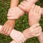 multiple hands holding each other to depict team work.